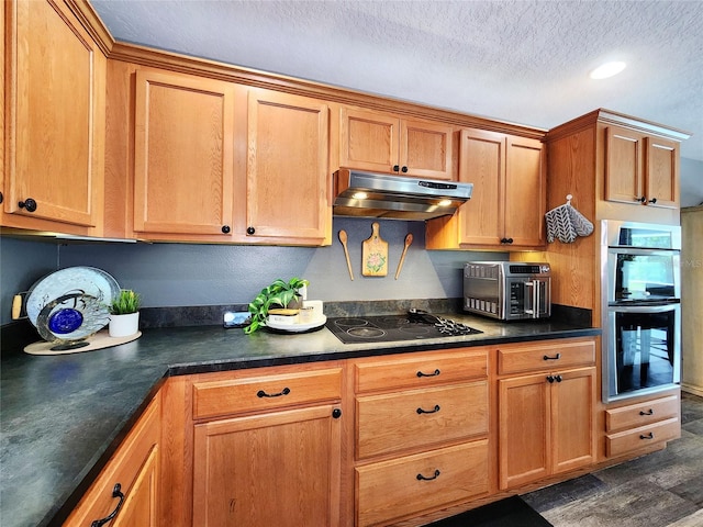 3112 Kearns Rd, Mulberry, FL 33860 - kitchen with black electric stovetop, double oven, under cabinet range hood, dark countertops, and a textured ceiling