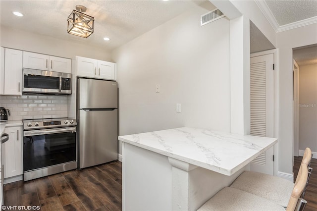 2207 S Carolina Ave Unit 10, Tampa, FL 33629 - kitchen with stainless steel appliances, dark wood-style flooring, white cabinetry, backsplash, and recessed lighting