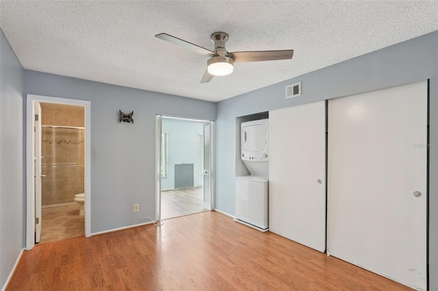 2370 Jamaican St Unit 44, Clearwater, FL 33763 - unfurnished bedroom featuring stacked washer and clothes dryer, wood finished floors, ensuite bath, a textured ceiling, and a closet