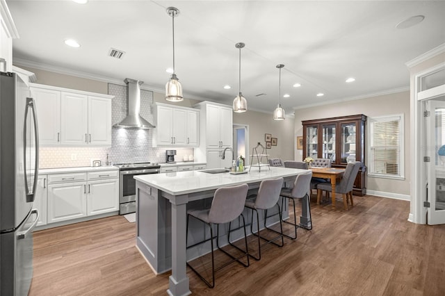 13252 SW 6th Ave, Newberry, FL 32669 - kitchen featuring wall chimney exhaust hood, stainless steel appliances, a kitchen breakfast bar, white cabinets, and a kitchen island with sink
