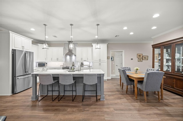 13252 SW 6th Ave, Newberry, FL 32669 - kitchen with stainless steel appliances, wall chimney range hood, decorative backsplash, a breakfast bar area, and white cabinets