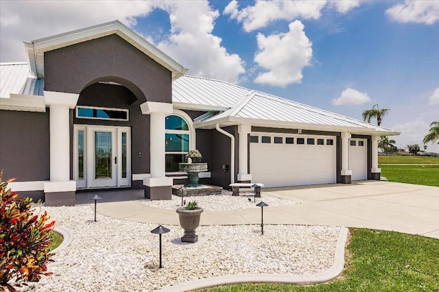 20 Bunker Ter, Rotonda West, FL 33947 - view of front facade featuring a metal roof, a garage, driveway, a standing seam roof, and stucco siding