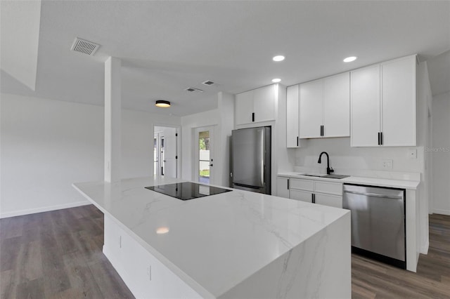 4957 N Cranberry Blvd, North Port, FL 34286 - kitchen featuring stainless steel appliances, dark wood-style flooring, white cabinets, a kitchen island, and recessed lighting
