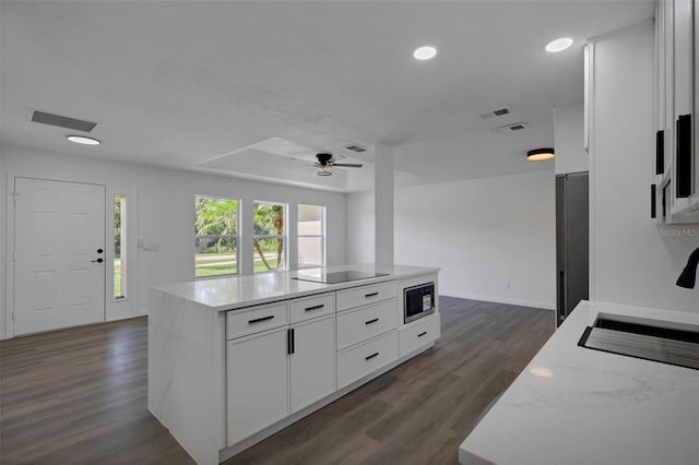 4957 N Cranberry Blvd, North Port, FL 34286 - kitchen featuring stainless steel microwave, black electric cooktop, dark wood-style flooring, a kitchen island, and recessed lighting