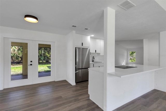 4957 N Cranberry Blvd, North Port, FL 34286 - kitchen with freestanding refrigerator, french doors, dark wood finished floors, black electric stovetop, and white cabinetry