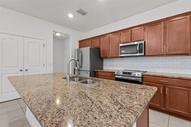 12124 Lake Blvd, Trinity, FL 34655 - kitchen featuring appliances with stainless steel finishes, an island with sink, light stone countertops, and light tile patterned floors