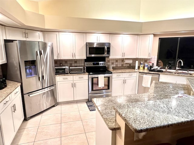 1304 N Jasmine Ave, Tarpon Springs, FL 34689 - kitchen with appliances with stainless steel finishes, decorative backsplash, light tile patterned flooring, and light stone countertops