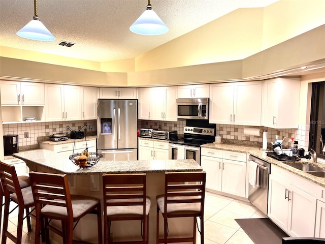 1304 N Jasmine Ave, Tarpon Springs, FL 34689 - kitchen with appliances with stainless steel finishes, lofted ceiling, a textured ceiling, a kitchen breakfast bar, and tasteful backsplash