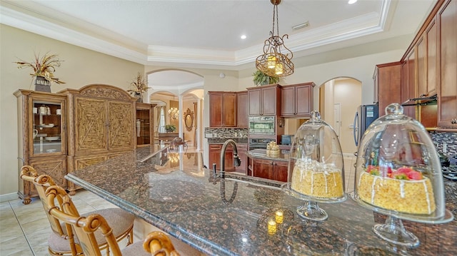15110 Sundial Pl, Lakewood Ranch, FL 34202 - kitchen with arched walkways, a raised ceiling, crown molding, backsplash, and a breakfast bar area