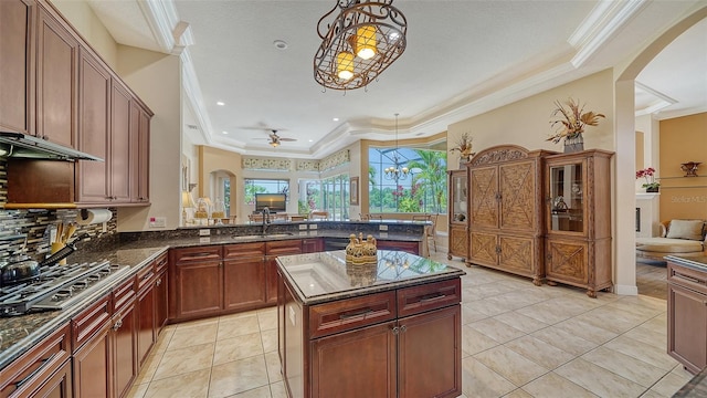 15110 Sundial Pl, Lakewood Ranch, FL 34202 - kitchen with stainless steel gas stovetop, arched walkways, ornamental molding, a ceiling fan, and a tray ceiling