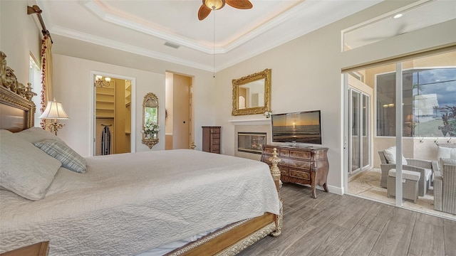 15110 Sundial Pl, Lakewood Ranch, FL 34202 - bedroom with access to outside, a raised ceiling, wood finished floors, ornamental molding, and a walk in closet