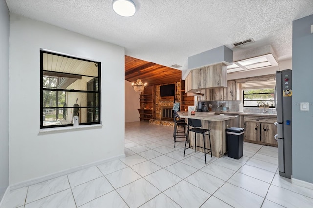 1116 Dagmar Ave, Spring Hill, FL 34606 - kitchen with freestanding refrigerator, a breakfast bar area, light countertops, a chandelier, and light tile patterned floors