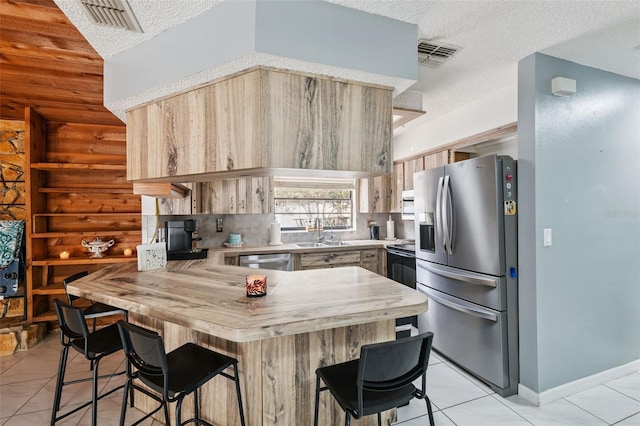 1116 Dagmar Ave, Spring Hill, FL 34606 - kitchen featuring appliances with stainless steel finishes, a peninsula, a textured ceiling, a kitchen breakfast bar, and light countertops