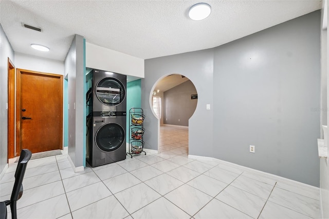 1116 Dagmar Ave, Spring Hill, FL 34606 - laundry area with stacked washer and clothes dryer, arched walkways, a textured ceiling, and light tile patterned floors