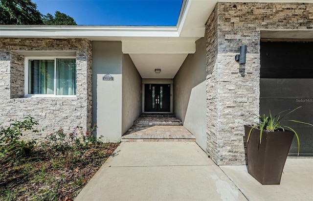1120 Lancer Ln, Tarpon Springs, FL 34689 - view of exterior entry with stone siding, stucco siding, and a garage