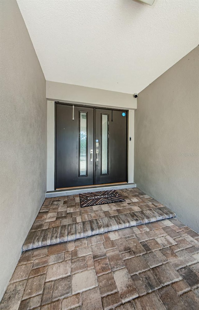 1120 Lancer Ln, Tarpon Springs, FL 34689 - property entrance with stucco siding and a security system