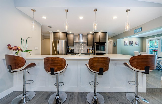 1120 Lancer Ln, Tarpon Springs, FL 34689 - kitchen featuring stainless steel appliances, dark wood-style flooring, light countertops, wall chimney exhaust hood, and recessed lighting