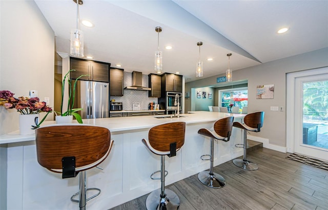 1120 Lancer Ln, Tarpon Springs, FL 34689 - kitchen featuring stainless steel refrigerator, wall chimney range hood, light countertops, decorative backsplash, and wood finished floors