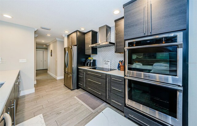 1120 Lancer Ln, Tarpon Springs, FL 34689 - kitchen featuring wall chimney range hood, stainless steel appliances, light wood-type flooring, light countertops, and decorative backsplash
