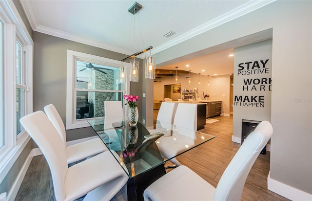 1120 Lancer Ln, Tarpon Springs, FL 34689 - dining space with light wood-style flooring, ornamental molding, and ceiling fan