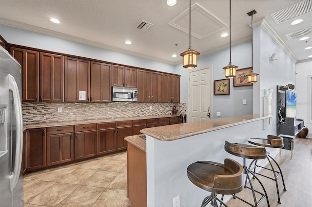 11571 84th Street Cir E Unit 106, Parrish, FL 34219 - kitchen with appliances with stainless steel finishes, ornamental molding, backsplash, a kitchen bar, and decorative light fixtures