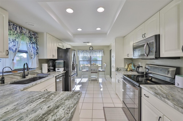 2510 Locksley St Unit 2510, Sun City Center, FL 33573 - kitchen featuring appliances with stainless steel finishes, a tray ceiling, white cabinetry, light stone counters, and light tile patterned floors