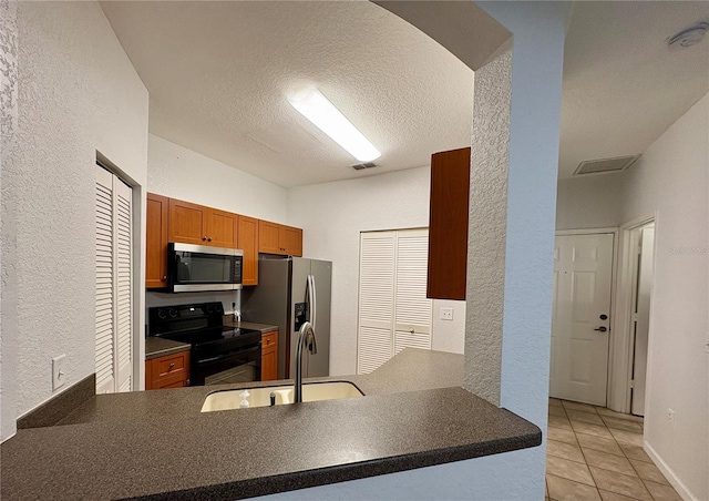 2148 Chianti Pl Unit 1310, Palm Harbor, FL 34683 - kitchen featuring stainless steel appliances, a textured wall, dark countertops, light tile patterned floors, and brown cabinetry