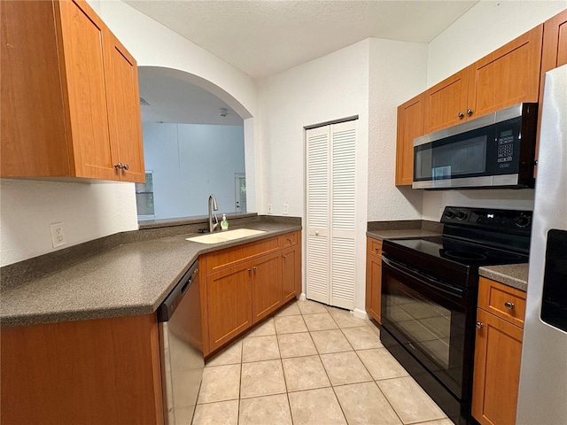 2148 Chianti Pl Unit 1310, Palm Harbor, FL 34683 - kitchen with stainless steel appliances, dark countertops, brown cabinets, and light tile patterned floors
