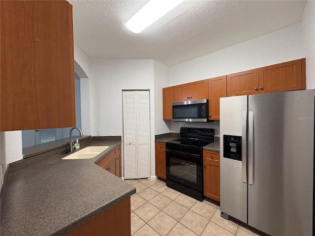 2148 Chianti Pl Unit 1310, Palm Harbor, FL 34683 - kitchen featuring appliances with stainless steel finishes, dark countertops, brown cabinetry, a textured ceiling, and light tile patterned flooring