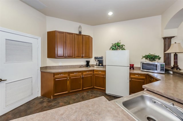 2148 Chianti Pl Unit 1310, Palm Harbor, FL 34683 - kitchen featuring freestanding refrigerator, stainless steel microwave, brown cabinetry, light countertops, and arched walkways