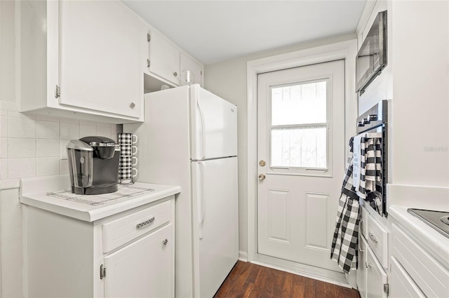 500 Glennes Ln Unit 206, Dunedin, FL 34698 - kitchen with freestanding refrigerator, backsplash, light countertops, white cabinetry, and dark wood-style floors