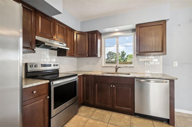 992 20th St SW, Largo, FL 33770 - kitchen featuring stainless steel appliances, under cabinet range hood, tasteful backsplash, light tile patterned floors, and light stone counters