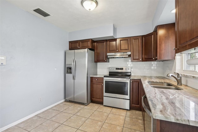 992 20th St SW, Largo, FL 33770 - kitchen with stainless steel appliances, under cabinet range hood, decorative backsplash, light stone countertops, and light tile patterned flooring
