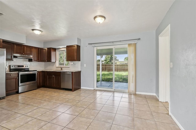 992 20th St SW, Largo, FL 33770 - kitchen with appliances with stainless steel finishes, under cabinet range hood, light countertops, backsplash, and light tile patterned flooring