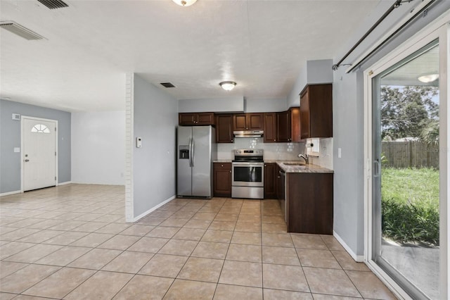 992 20th St SW, Largo, FL 33770 - kitchen with stainless steel appliances, light tile patterned floors, under cabinet range hood, and healthy amount of natural light