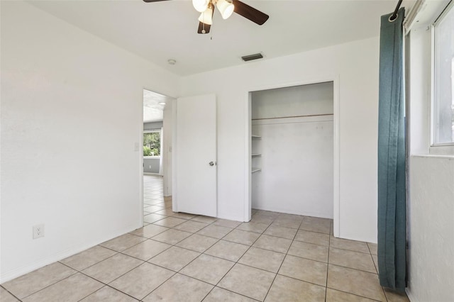 992 20th St SW, Largo, FL 33770 - unfurnished bedroom with multiple windows, light tile patterned flooring, a closet, and ceiling fan