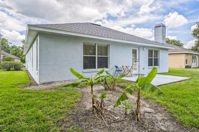 1754 Turtle Rock Dr, Lakeland, FL 33803 - rear view of house featuring stucco siding, a patio area, a lawn, and a shingled roof