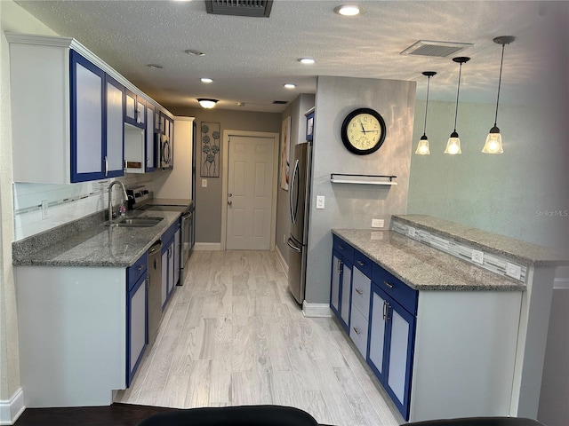 3260 Parkway Pl, Palm Harbor, FL 34684 - kitchen with blue cabinetry, stainless steel appliances, light wood finished floors, a peninsula, and a textured ceiling