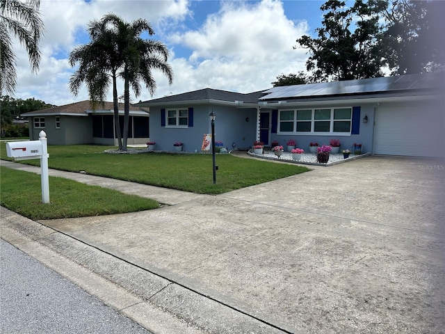 3260 Parkway Pl, Palm Harbor, FL 34684 - ranch-style home with roof mounted solar panels, a front lawn, driveway, stucco siding, and an attached garage