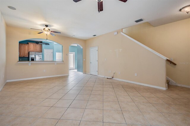 14167 Stilton St, Tampa, FL 33626 - unfurnished living room featuring ceiling fan, light tile patterned floors, arched walkways, and stairway