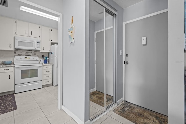 2700 Bayshore Blvd Unit 2312, Dunedin, FL 34698 - kitchen with white appliances, light countertops, light tile patterned floors, white cabinetry, and backsplash