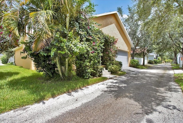 7310 S Shamrock Rd, Tampa, FL 33616 - view of property exterior featuring stucco siding, driveway, and a garage