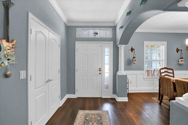 7310 S Shamrock Rd, Tampa, FL 33616 - foyer featuring arched walkways, dark wood finished floors, decorative columns, crown molding, and wainscoting