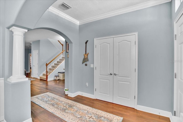 7310 S Shamrock Rd, Tampa, FL 33616 - foyer entrance with decorative columns, wood finished floors, arched walkways, ornamental molding, and stairway