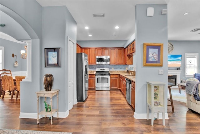 7310 S Shamrock Rd, Tampa, FL 33616 - kitchen with appliances with stainless steel finishes, brown cabinets, dark wood finished floors, tasteful backsplash, and recessed lighting