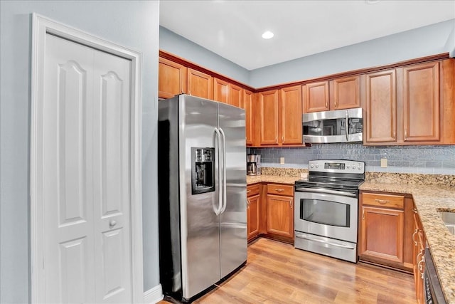 7310 S Shamrock Rd, Tampa, FL 33616 - kitchen featuring stainless steel appliances, tasteful backsplash, light wood finished floors, and brown cabinets