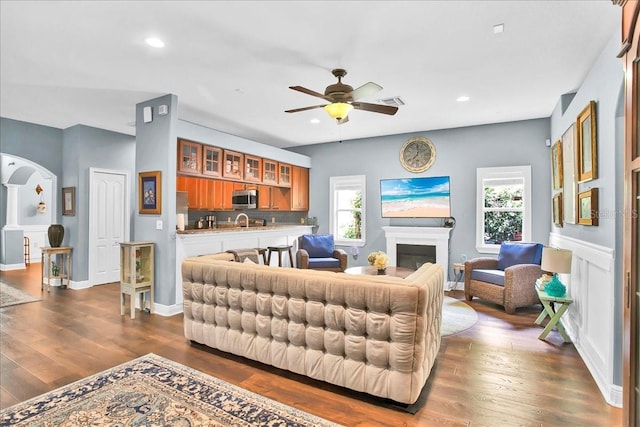 7310 S Shamrock Rd, Tampa, FL 33616 - living room with a ceiling fan, dark wood-style flooring, arched walkways, a glass covered fireplace, and recessed lighting