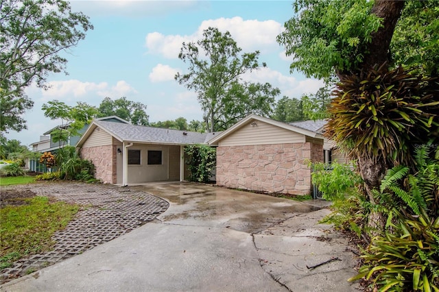 3129 W Paris St, Tampa, FL 33614 - view of front of house with stone siding, driveway, and a carport