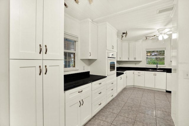 102 W N Branch Rd, Ruskin, FL 33570 - kitchen with oven, white cabinets, dark countertops, a ceiling fan, and light tile patterned flooring