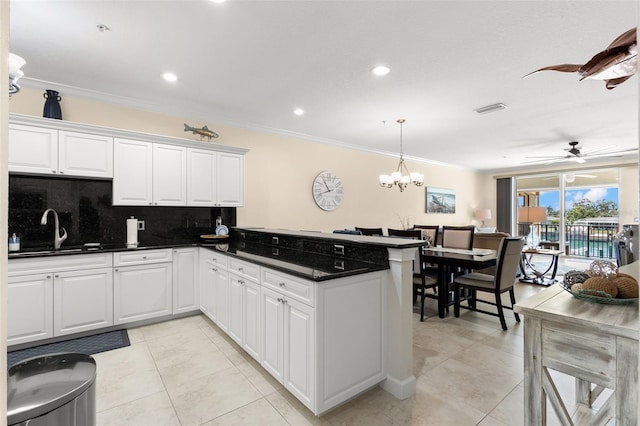 300 Capri Blvd Unit 3, Treasure Island, FL 33706 - kitchen with tasteful backsplash, crown molding, light tile patterned floors, a peninsula, and white cabinetry